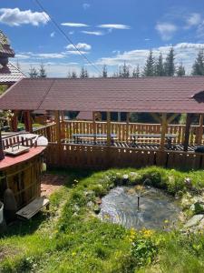 a wooden pavilion with a pond in a yard at Pensiunea Casa OLLY in Muntele Cacovei