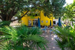a yellow building with chairs and umbrellas in a courtyard at B&B Villa Marta - New Opening 2026 in Medulin