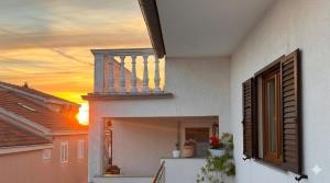 a house with a balcony with a sunset in the background at Apartment Niko in Pakoštane