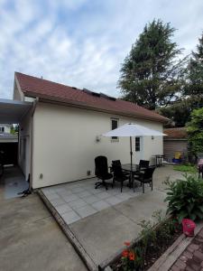a patio with a table and chairs and an umbrella at Private Room in Guest House, Near the New Oakridge Mall & Transit - Near Langara 49th Station in Vancouver