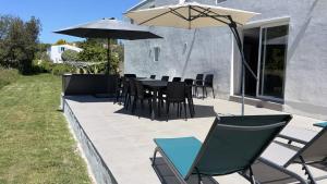 a patio with a table and chairs and an umbrella at L'îlo'T in Ker Pierre Borny