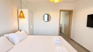 a white bedroom with a bed and a mirror at Ambra Luxury Suite 15 in Kallithea Halkidikis