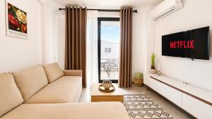 a living room with a couch and a tv at Ambra Luxury Suite 15 in Kallithea Halkidikis