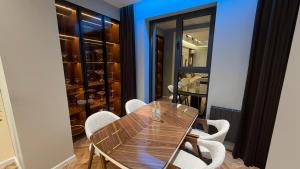 a dining room with a wooden table and white chairs at Zafran Smart Luxury Suite in Dushanbe