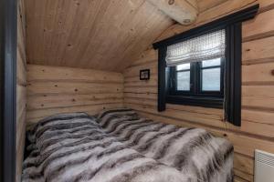 a bed in a log cabin with a window at Utsikten in Vågsli