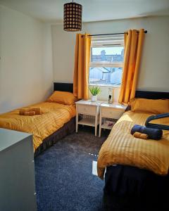 a bedroom with two beds and a window with orange curtains at Phoenix in Derry Londonderry