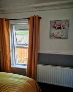a bedroom with a window with an orange curtain at Phoenix in Derry Londonderry +10 photos