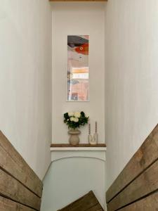 a white hallway with a vase of flowers on a shelf at Seeidyll an der Wublitz in Werder +87 photos