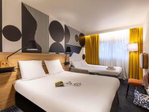a hotel room with a large white bed and chairs at Mercure Metz Centre in Metz +104 photos