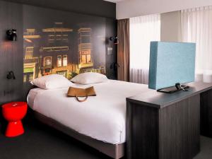 a bedroom with a large white bed with a painting on the wall at Mercure Hotel Tilburg Centrum in Tilburg