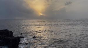 a sunset over the ocean with rocks in the water at Peaceful Stay in Malvan