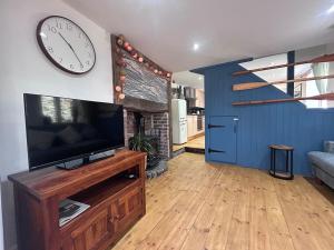 a living room with a tv and a clock on a wall at Forge Cottage in Polperro
