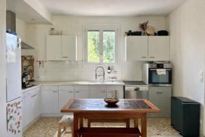 a kitchen with white cabinets and a wooden table at House with large garden Audenge in Audenge