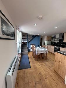 a living room with a table and a kitchen at Forge Cottage in Polperro