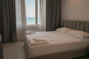 a bedroom with a bed with white sheets and a window at MiraMar Hotel in Shëngjin