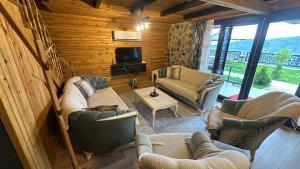 a living room with couches and chairs and a television at Lefkali HOME in Çınarlık