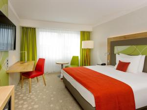 a hotel room with a large bed and a desk at Mercure Hotel Saarbrücken City in Saarbrücken +51 photos