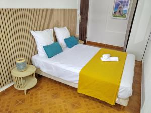 a small bedroom with a bed with a yellow table at La Casa Créole, spa, 3 ch, 2 sdb, centre de la Guadeloupe in Les Abymes