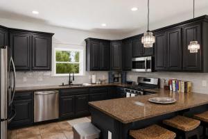 a kitchen with black cabinets and a granite counter top at St George Island Bay Front Pool in St. George Island +53 photos