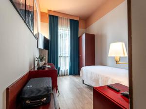a hotel room with a bed and a table with a desk sidx sidx sidx sidx at Mercure Bologna Centro in Bologna