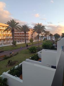 a view of a building with palm trees in the background at il centro delle vacanze in Playa de las Americas