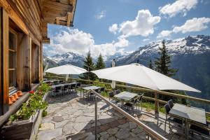 a patio with tables and umbrellas in front of a building at Tällihütte in Gadmen +46 photos