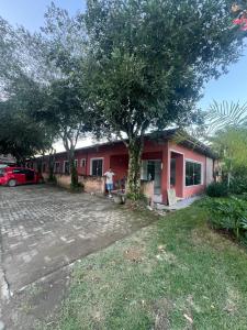 a man standing in front of a red house at Hotel Betel Rio Bonito in Estaçao Realengo