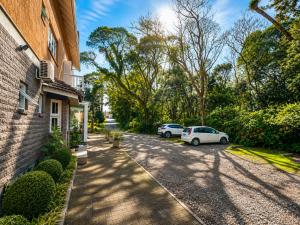 a driveway with two cars parked next to a building at Pousada Nosso Lar in Gramado