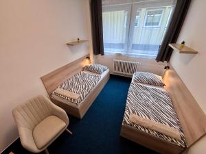a room with two beds and a chair and a window at Sporthostel Scandinavia in Prague