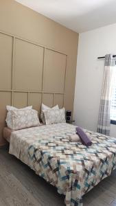a bedroom with a bed with a blanket and pillows at Résidence LE MÄYSA in Sada