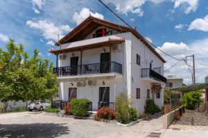 a white house with a balcony on a street at Tsimiklis Apartments in Finikounta