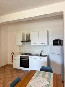 a kitchen with white cabinets and a table and a stove at Appartamenti Cala d'Ambra in San Teodoro