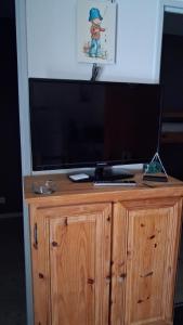 a flat screen tv on top of a wooden cabinet at Parc résidentiel Les Moussaillons in Hourtin +16 photos