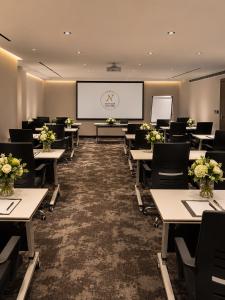a conference room with tables and chairs and a screen at Luxury Night Hotel Al Yasmin in Riyadh