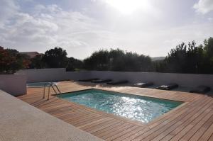 a swimming pool on top of a wooden deck at Résidence Maora Village in Bonifacio