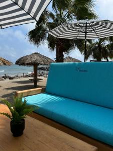 a blue couch under an umbrella on the beach at PELÍCANOS Hotel & Beach Club in El Zapote