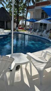 a white table and chairs next to a swimming pool at PELÍCANOS Hotel & Beach Club in El Zapote
