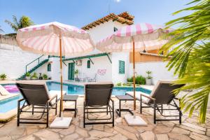 a group of chairs and umbrellas next to a pool at Elsi Pousada in Búzios