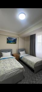 a bedroom with two beds and a window with at Kyialym Hotel in Bishkek