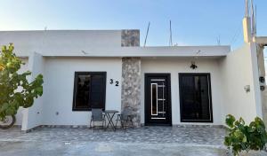 a white house with two chairs and a door at TinyHouseMX2 Comodidad, lujo y playa que se disfruta in Barre De Navidad