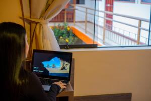 a woman sitting at a table with a laptop computer at Hotel Sol de Belén Cajamarca in Cajamarca