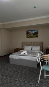 a bedroom with a bed and a chair in it at Kyialym Hotel in Bishkek