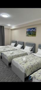 a room with three beds and a painting on the wall at Kyialym Hotel in Bishkek