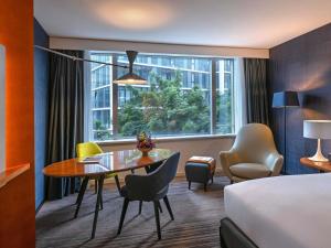 a hotel room with a table and chairs and a bed at Sofitel Luxembourg Europe in Luxembourg +56 photos