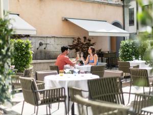 Ein Mann und eine Frau sitzen an einem Tisch mit Weingläsern in der Unterkunft Hotel Rotary Geneva - MGallery in Genf