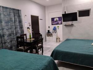 a bedroom with two beds and a table and a tv at Departamentos Oasis in Champotón
