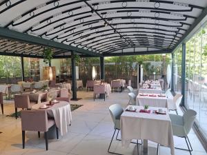 a restaurant with white tables and chairs and windows at Mercure Ajaccio in Ajaccio
