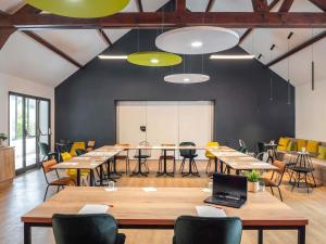 a conference room with tables and chairs and a whiteboard at ibis Beaune Centre in Beaune