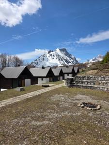 a house with a snow covered mountain in the background at Katun Komovi in Andrijevica