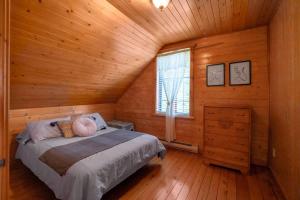 a bedroom with a bed in a wooden cabin at Rustic Chalet Hideaway - Hot Tub & Trail Access in Saint-Léonard-de-Portneuf
